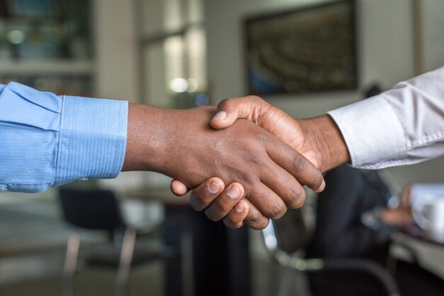 Duas pessoas dando um aperto de mão exemplificando a responsabilidade social corporativa